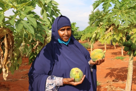 Habiba holding pawpaw grown and harvested from her farm in Kenya